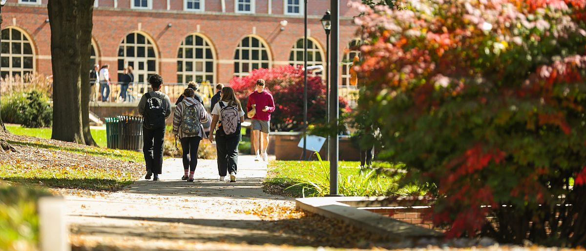 Students walking on campus in the distance on a fall day.